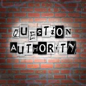 A brick wall on which spotlighted text reads "Question Authority".